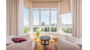 Living room with solar shades partially drawn, showcasing an outdoor balcony view through large glass doors.